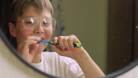 Niño-Feliz-Cepillando-Los-Dientes-Frente-Al-Espejo,-Tiro-Estático-Medio