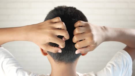 teenage boy scratching head against black background