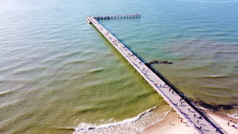 people enjoy sunny day on palanga bridge, aerial descend view