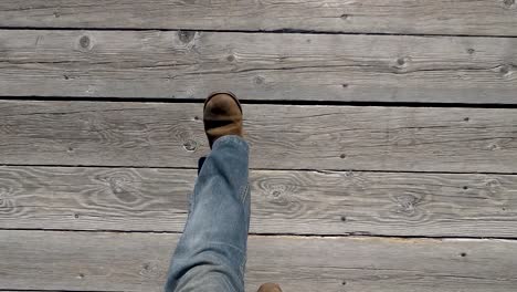 Walking on a boardwalk looking down at leg and feet with boots on