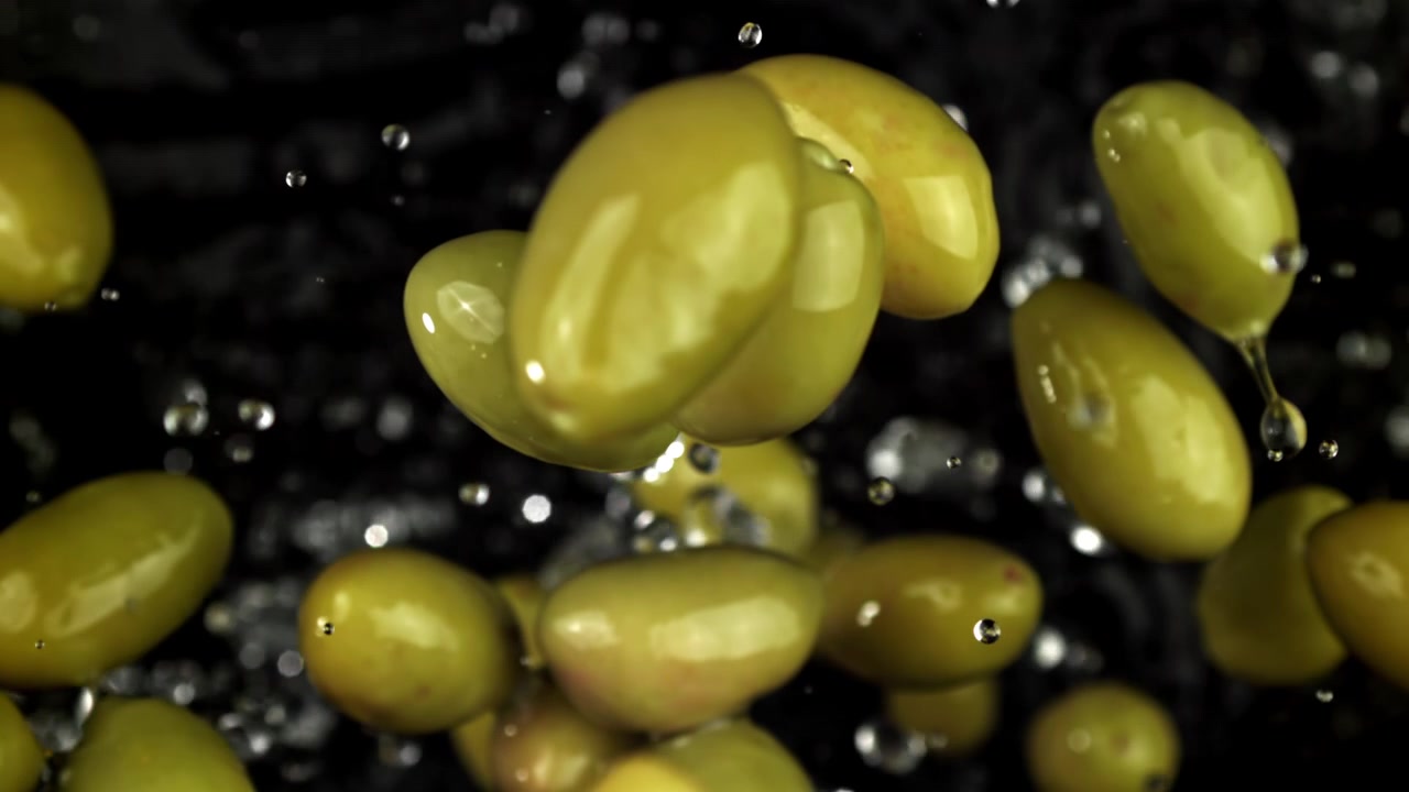 Olive verdi fresche con goccioline d'acqua che cadono al rallentatore.