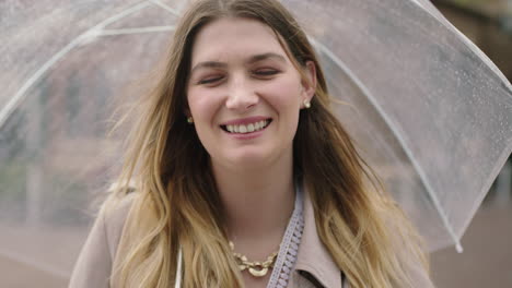 retrato de una joven rubia feliz sonriendo con confianza sosteniendo un paraguas disfrutando de un día frío y lluvioso