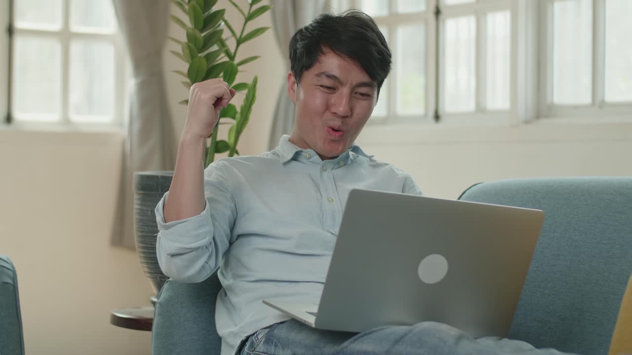 Male Use Laptop Computer And Celebrating In Living Room , Video In 4K