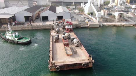 barcaza cargada con camiones hormigonera tirada al puerto por un remolcador en la bahía de hong kong, vista aérea
