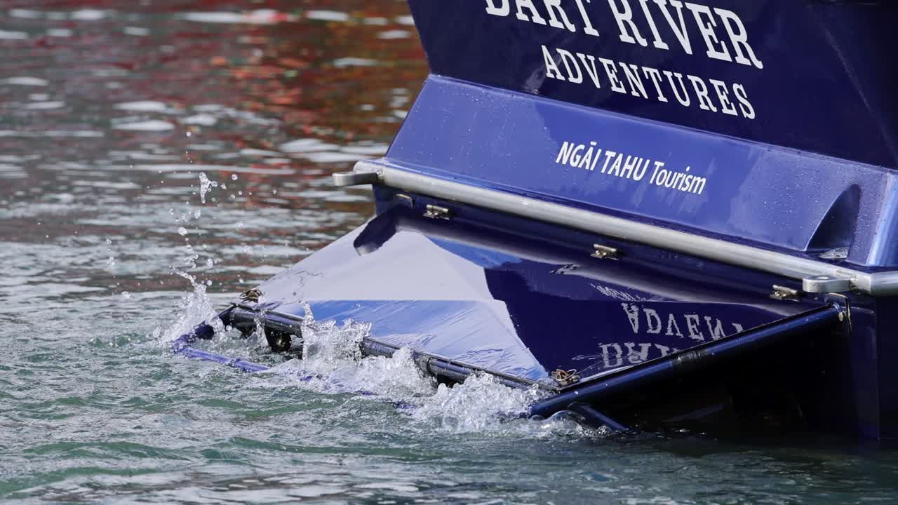 A jet boat maneuvers through Dart River, showcasing dynamic water interaction and vibrant blue design