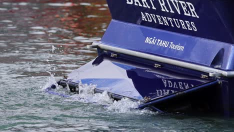 a jet boat maneuvers through dart river, showcasing dynamic water interaction and vibrant blue design
