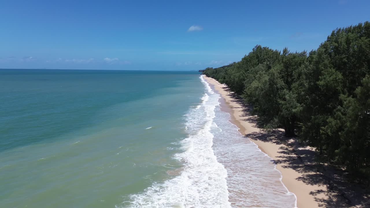 Aerial drone footage of Long Beach in Koh Lanta Thailand showing turquoise ocean, golden sandy coastline, palm and pine trees, tropical vegetation and wide open seascape with no people