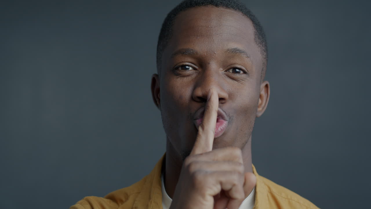 homem com o dedo nos lábios