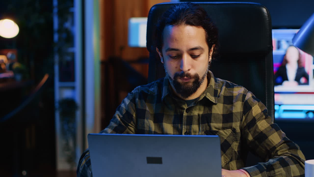 hombre sonriente sentado en el escritorio de la oficina de casa y escribiendo en el teclado de la computadora portátil,