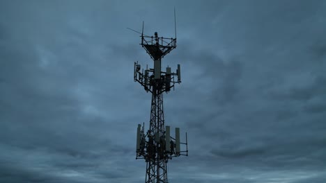 Cell-tower-against-dark-cloudy-sky-at-dusk