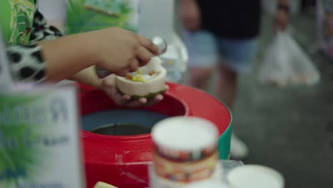 a person scooping coconut ice cream at a street food market