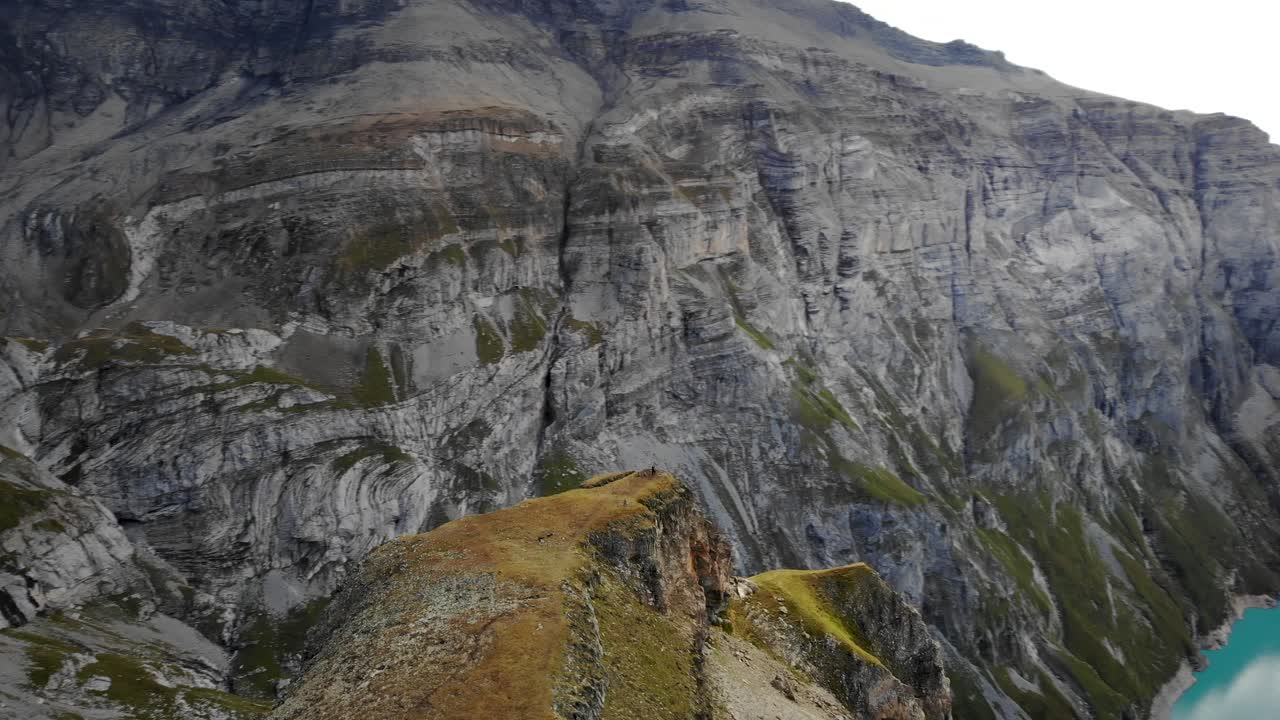 una vista aérea giratoria del mirador del acantilado del lago limernsee en glarus, suiza, con excursionistas disfrutando de la vista de los acantilados de los alpes suizos, el paisaje y el agua turquesa