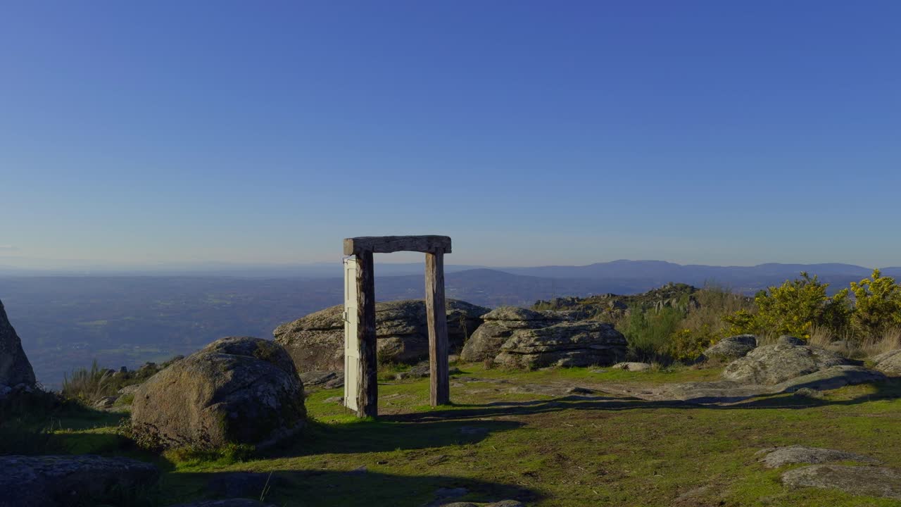 excelente vista de la cima de una montaña con una puerta vieja y grandes rocas con sol