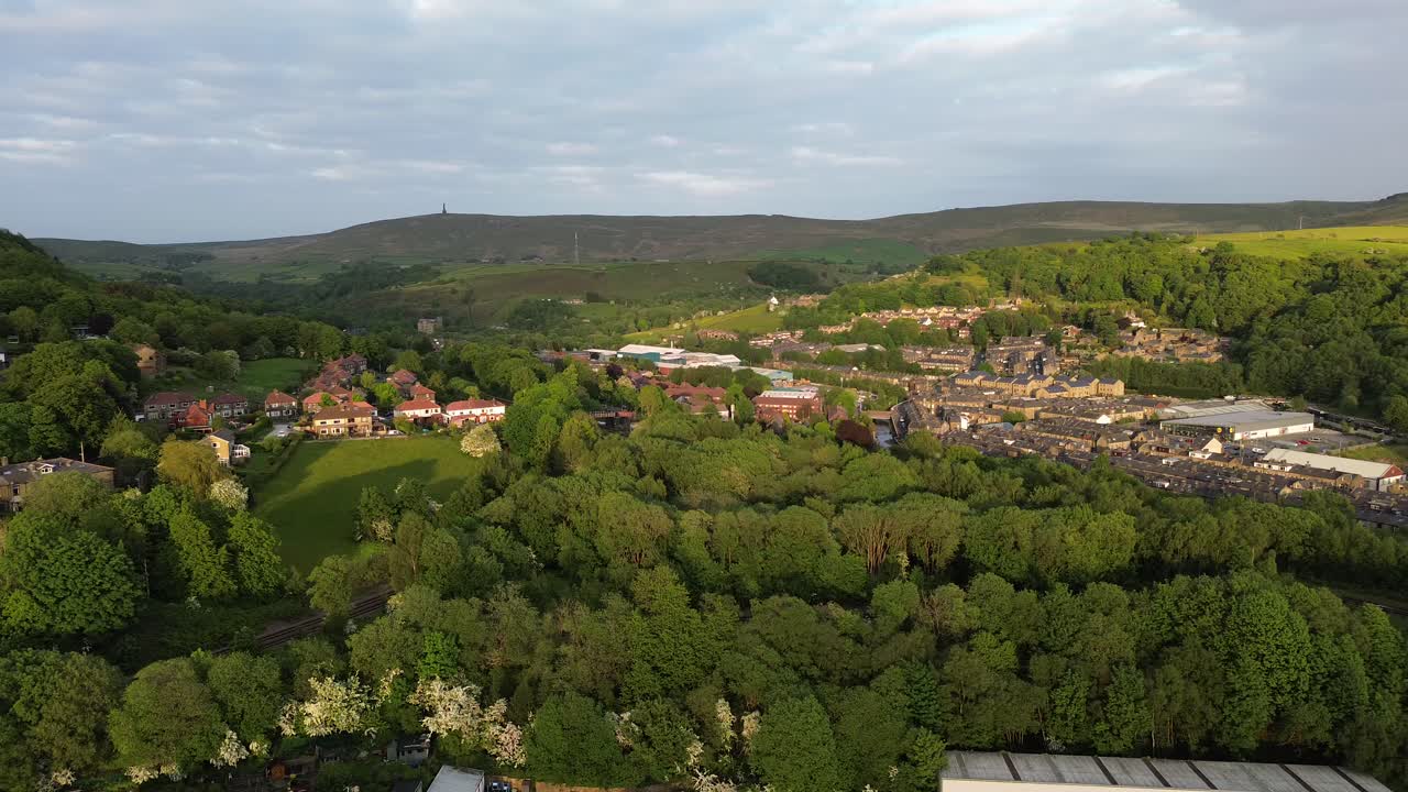 drone de la mano derecha panorámica de las cumbres de las copas de los árboles en la soleada pequeña ciudad de todmorden ubicada en inglaterra