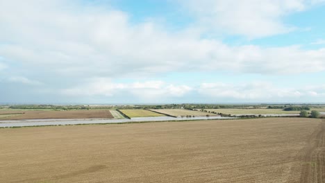 aerial drone footage on the east coast of north yorkshire flying over a ploughed farmer's field with other fields and sea in the far distance