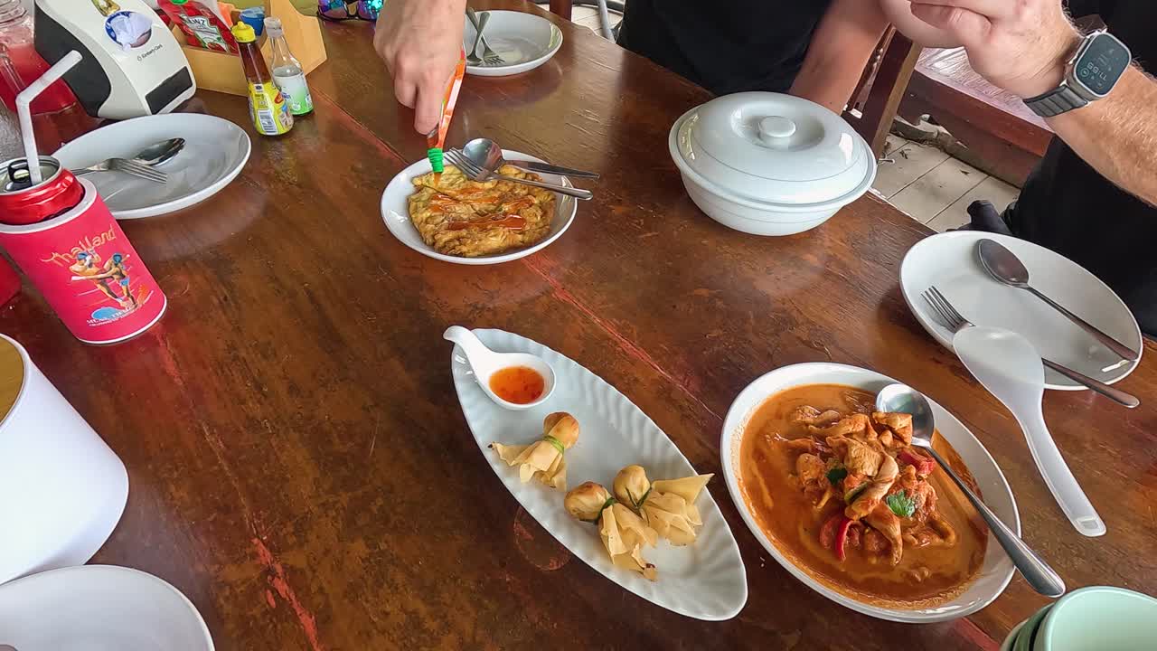 Diners enjoy a spicy omelette with sauce at a street food stall in Phuket, Thailand. Vibrant colors and casual atmosphere