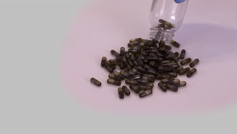 Brown-capsules-filled-with-cannabis-oil-poured-onto-table-in-slo-mo