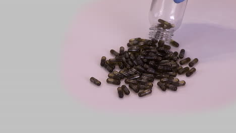 brown capsules filled with cannabis oil poured onto table in slo mo