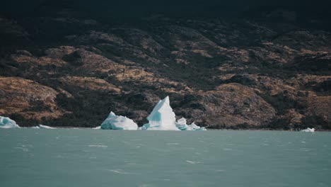 icebergs in argentino lake against the mountain seen from a sailing boat