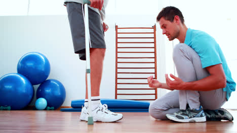 Fisioterapeuta-Ayudando-Al-Paciente-A-Caminar-Con-Muletas.