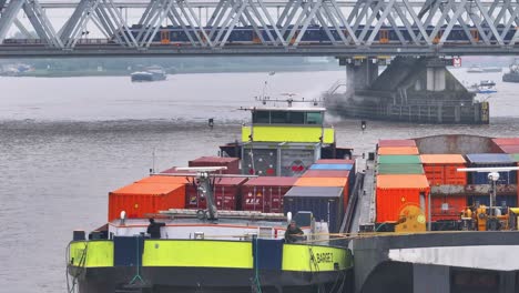 cargo ship with containers and train on bridge over river