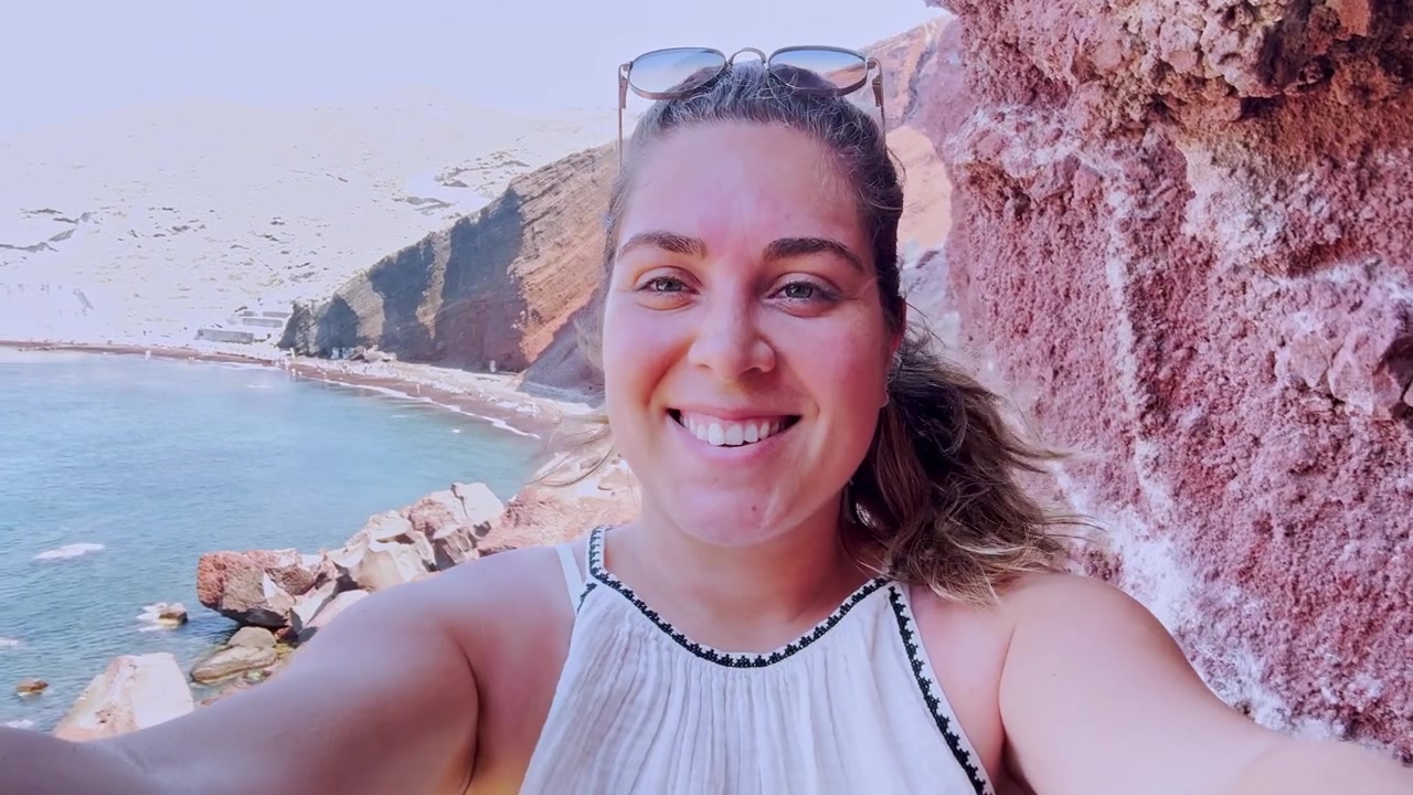 Influencer donna che si scatta un selfie sulla spiaggia rossa, a Santorini.
