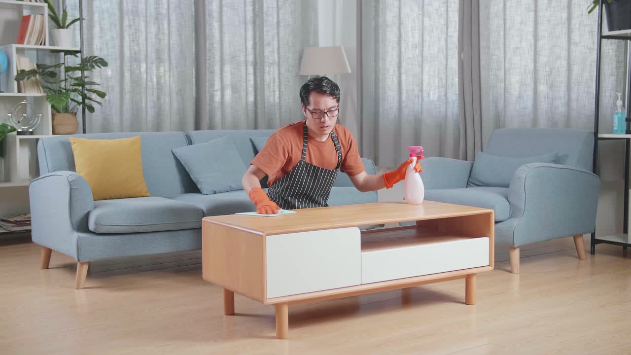 사람 은 거실 에서 커피 테이블 을 청소 하고 있다