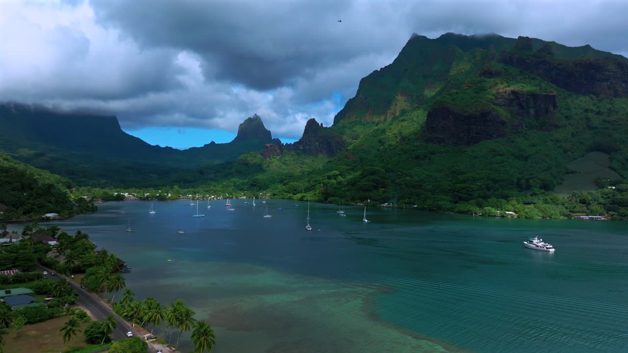 Mo'orea, Bora Bora, Franska Polynesien, flygdrönare, tropisk kryssning i Söderhavet, motorbåtar, segelbåtar, Opunohu Bay offentliga strand, djupa turkosa laguner, taggiga toppar, solig morgon, bilar, helikopter.