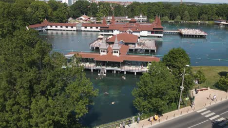 Drone-shot-through-trees-closing-in-on-buildings-in-the-He-viz-Lake-of-hungary