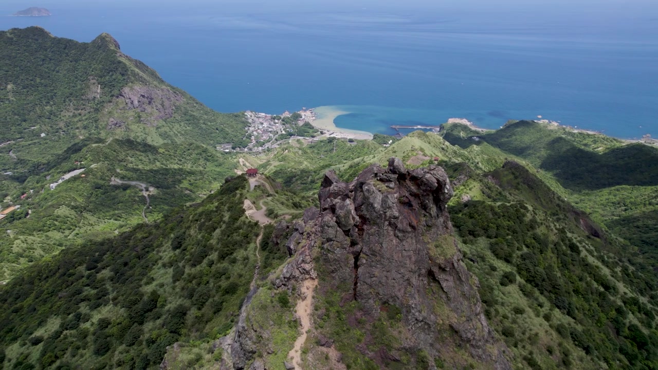 Vacker flygbild av Teapot Mountain bakom en klippig udde, belägen nära New Taipei City, Taiwan, med den vackra Stillahavskusten i bakgrunden.