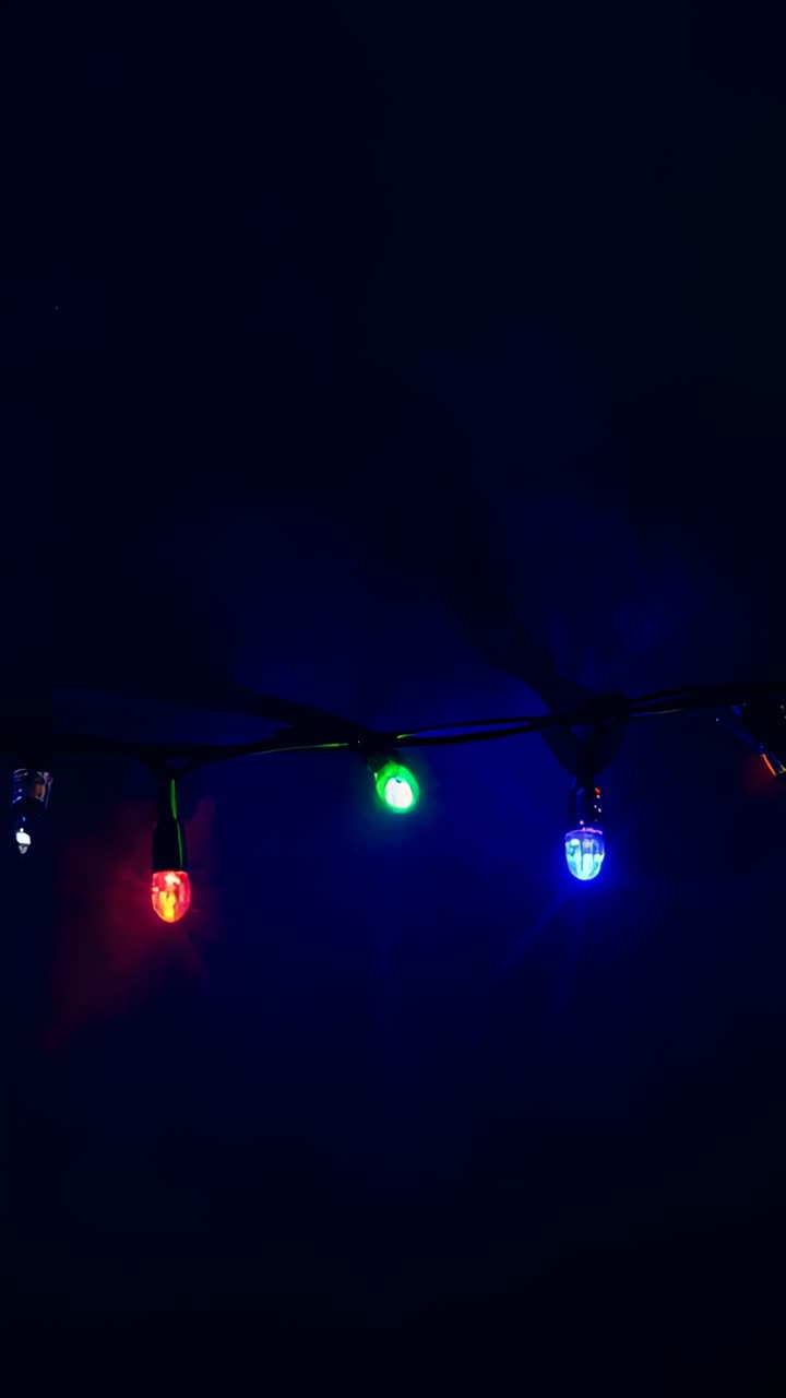 Vertical video: Shifting exposure showing three bulbs on string wire shifting halos in dim room