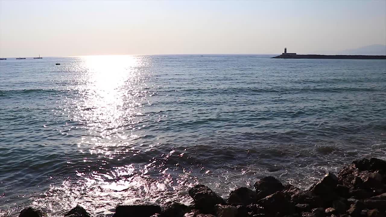 등대가 배경에 있는 일몰의 잔잔한 바다 바위 해변 풍경