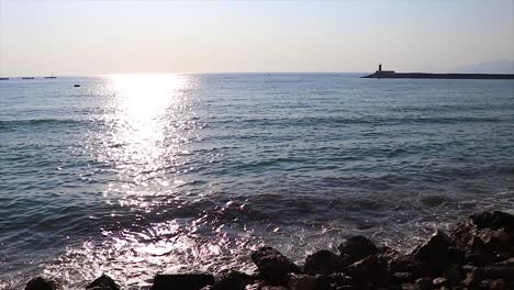 calm sea rocky beach landscape at sunset with a lighthouse in the background