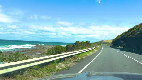 a car journey along the great ocean road, capturing coastal views and lush greenery under bright daylight