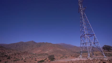 torre eléctrica de alto voltaje en un paisaje montañoso contra un claro cielo azul, revelando pan, vista panorámica