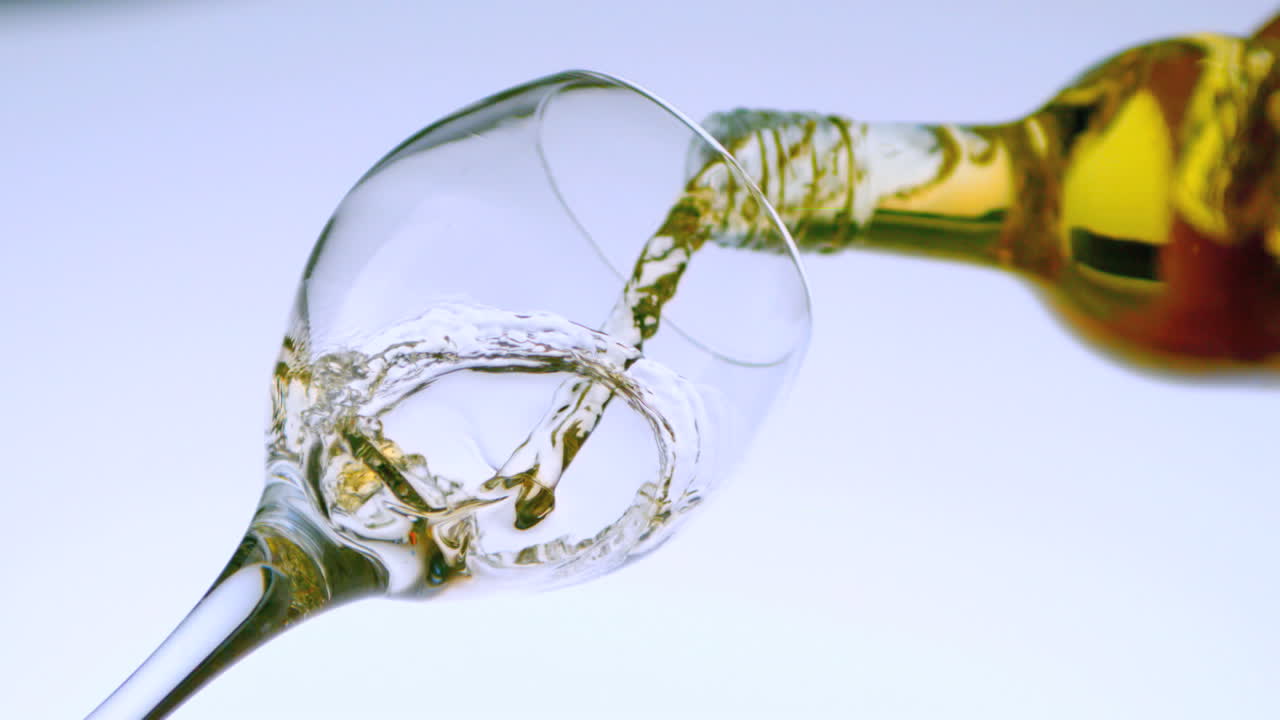 Vino bianco che si versa in un bicchiere, vista dal basso