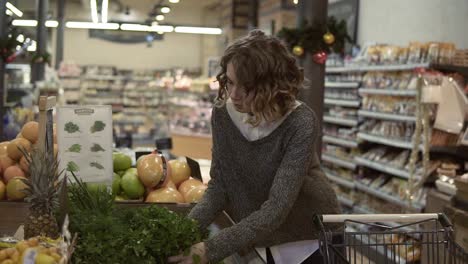 young woman buying ooganic food in supermarket. female taking green fresh parsley in grocery store. choosing good pale. slow motion. healthy lifestyle concept