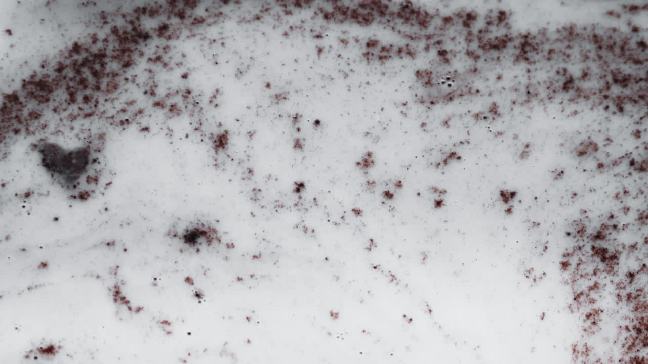 진한 빨간색 입자가 유백색 액체, 추상에서 소용돌이치고 표류합니다.