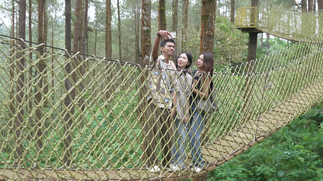 Asian Friends Taking Selfie on Forest Rope Bridge in Indonesia