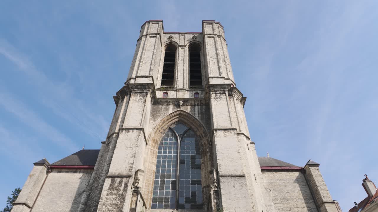 Facade of Saint Michael's Church in Ghent, showcasing stunning Gothic architecture with imposing windows and intricate details on a pleasant sunny day.