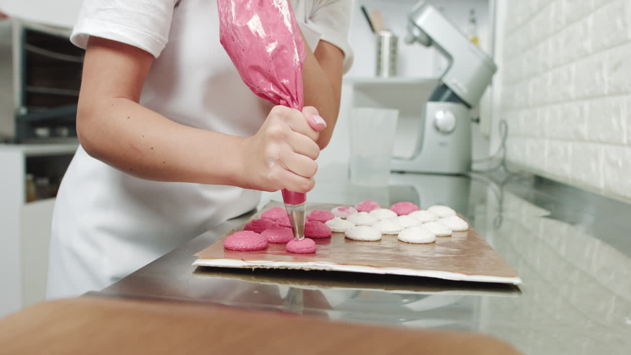 Woman decorating macarons with a pastry bag