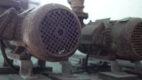 old and rusted water pump motor and pipes. tilt shot from right to left.