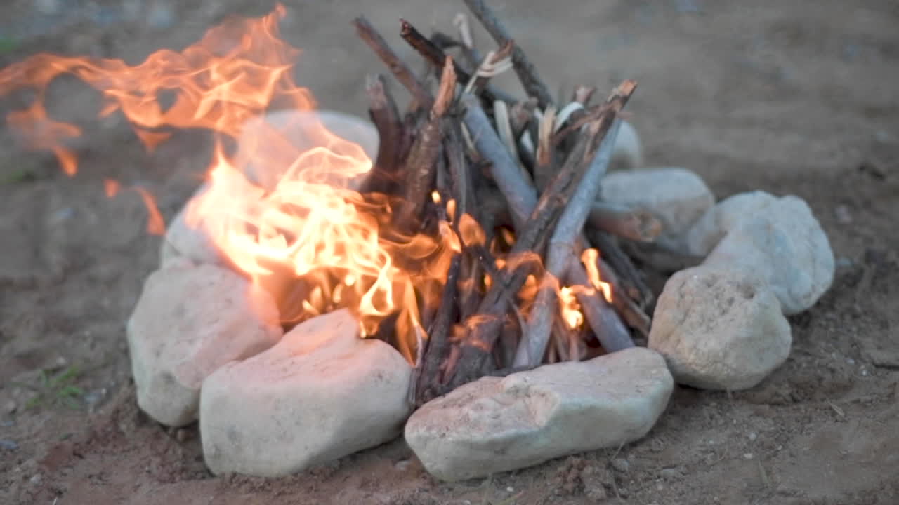 campfire made from wood and a surrounded by small rocks, shot with slow motion in a selective focus