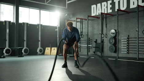 man working out with battling ropes in gym