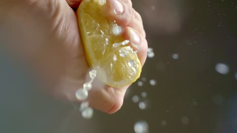 a person squeezes a lemon so juice comes out of it