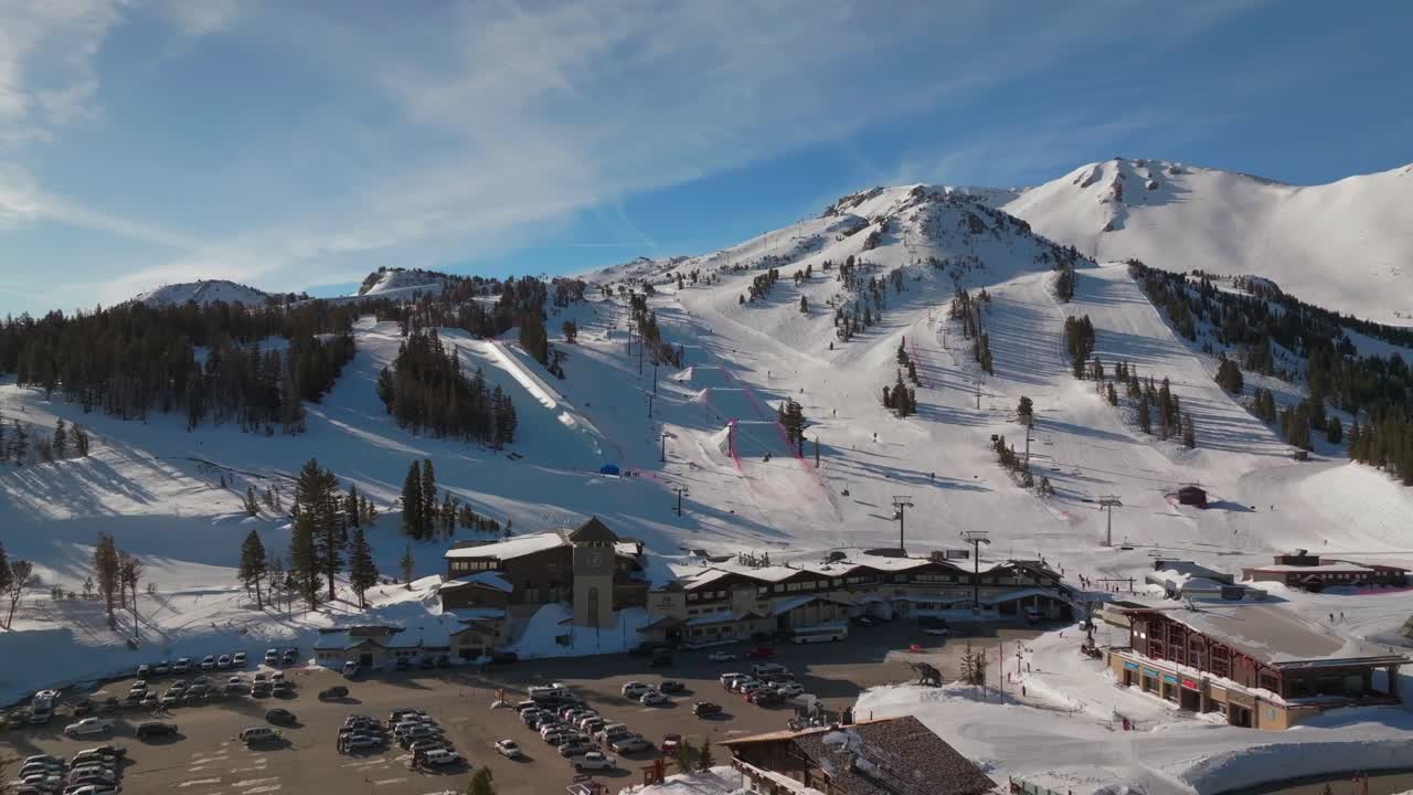 Mammoth Mountain ski resort spring Main Lodge California aerial drone Unbound Terrain Parks panorama landscape ski snowboard trail runs chairlift gondola cars parking lot sunny blue sky circle left