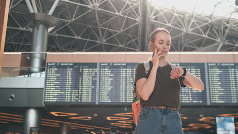 Woman-talking-on-the-phone-discussing-the-details-of-his-trip-and-booking-a-car-after-landing.-A-woman-standing-at-the-airport-calls-a-taxi-on-the-phone