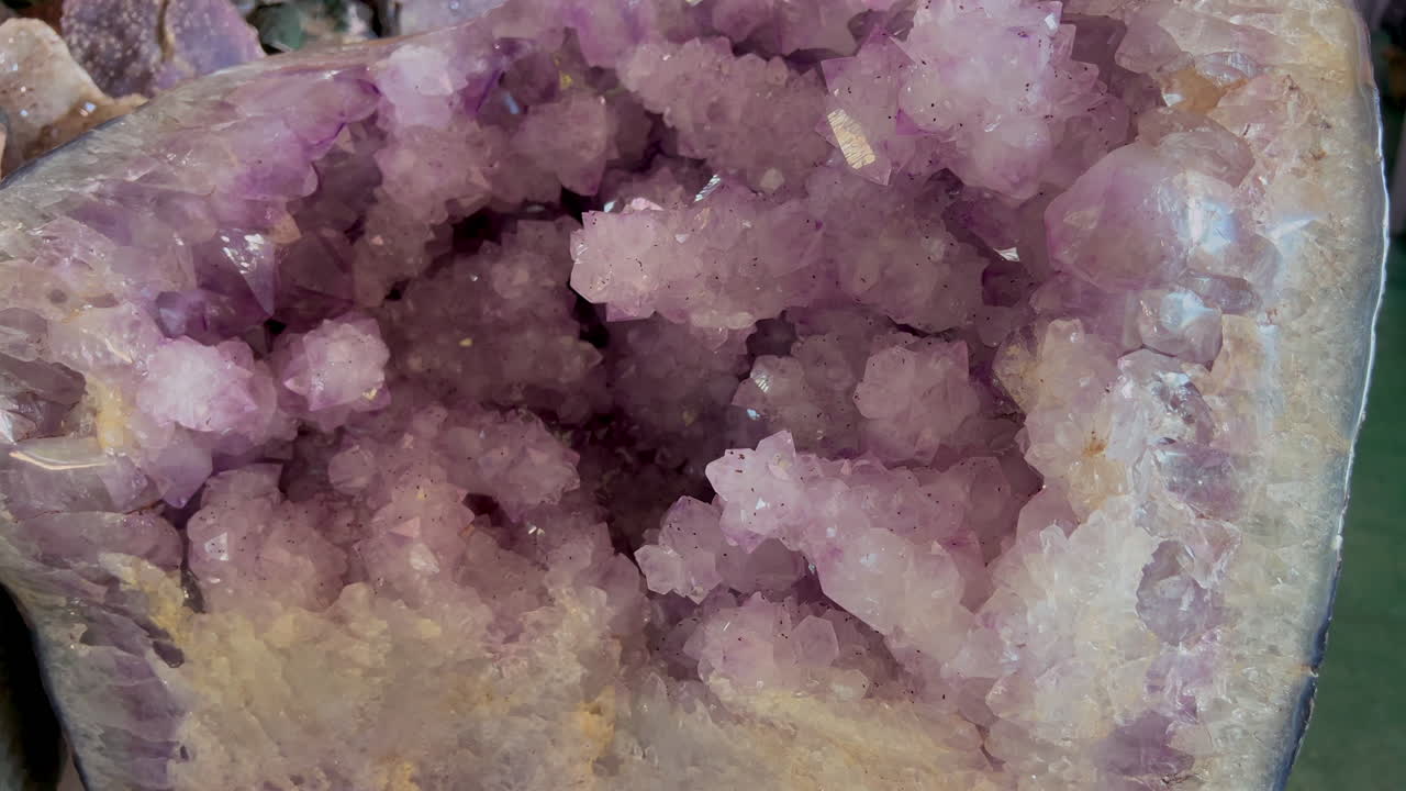 L'interno di un geode di ametista con pallide e complesse formazioni cristalline rivela delicate trame scintillanti in un primo piano dettagliato.