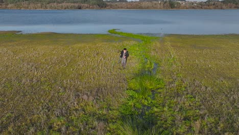 Fotograf-Mit-Kamera-Auf-Stativ-Beim-Spaziergang-Auf-Dem-Feld-Am-See