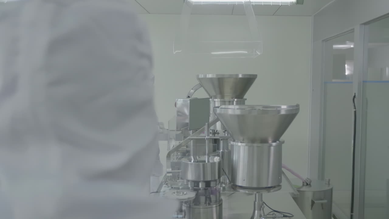 Workers in lab coat working protective gear on Pharmaceutical Production Line in Cleanroom Filling vials with Medication